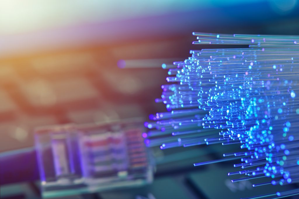 Fiber optics in blue, close up with ethernet and keyboard background, warm lens flare fibre-broadband-and-leased-lines